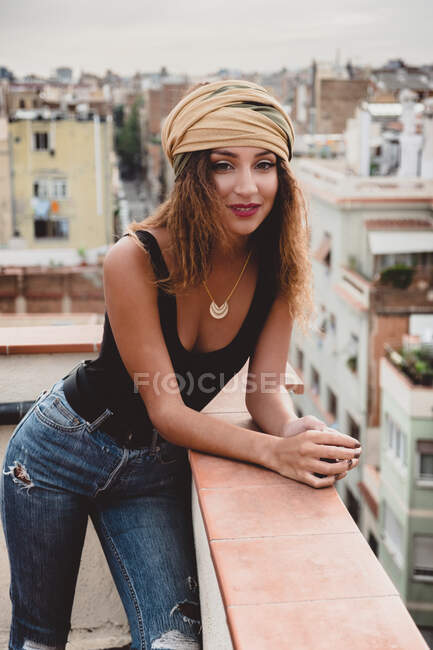 Jeune femme en mouchoir sur la tête debout sur le toit — Photo de stock