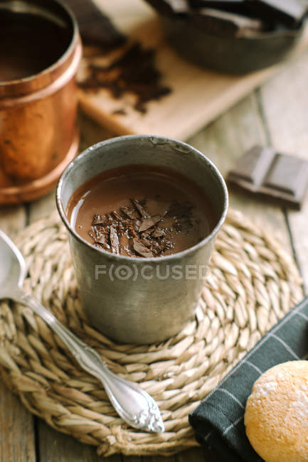 Taza de chocolate caliente con trozos de chocolate cubriendo la mesa de madera - foto de stock