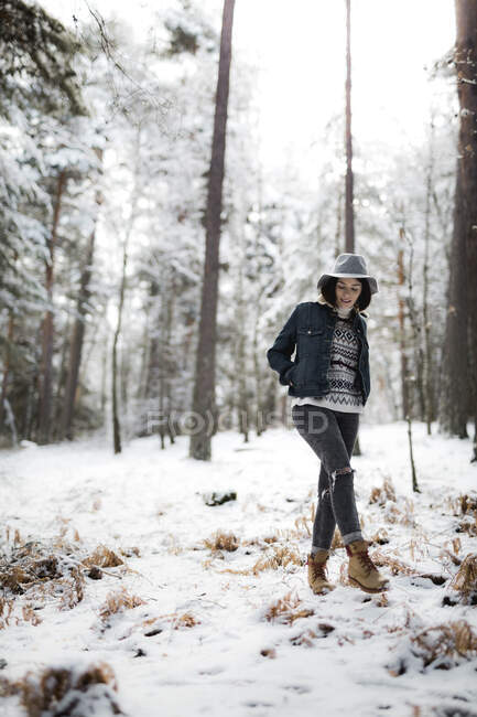 Jolie jeune femme en tenue élégante regardant loin tout en se tenant près d'un arbre couvert de neige par temps froid dans une magnifique campagne — Photo de stock