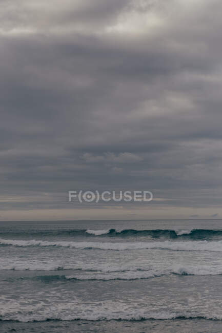 Grandes olas bajo el cielo nublado - foto de stock