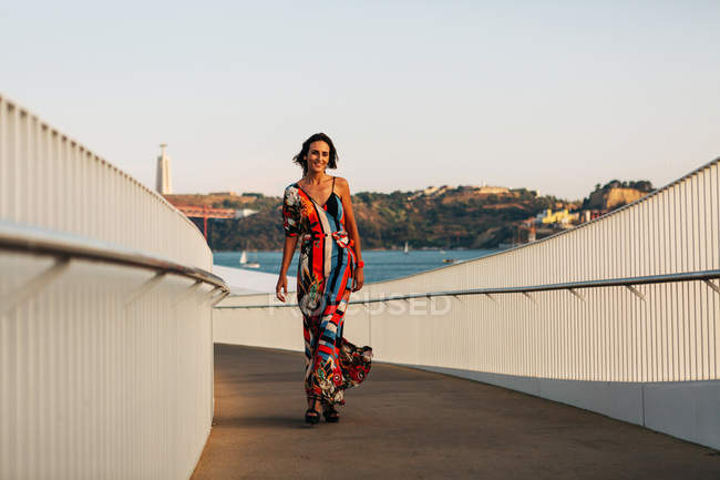 Mulher elegante em vestido longo andando na ponte na cidade de verão — Fotografia de Stock