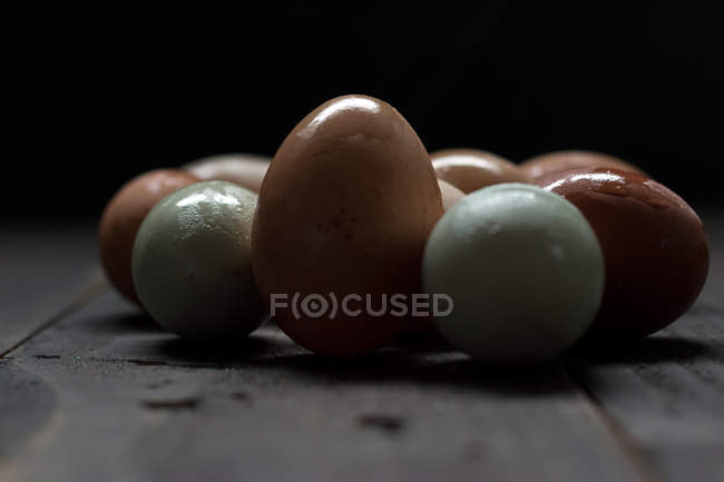 Oeufs blancs et bruns avec coquille mouillée sur table en bois foncé — Photo de stock