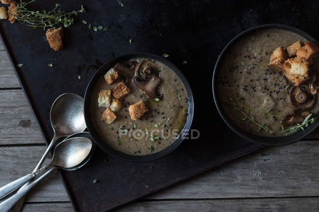 Грибний крем-суп з грінками в мисках на дерев'яному столі — стокове фото