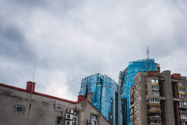 Облака, текущие в небе над старыми и современными высотными зданиями в городе — стоковое фото