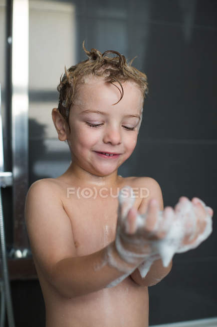 Brincalhão menino brincando com espuma no banheiro — Fotografia de Stock