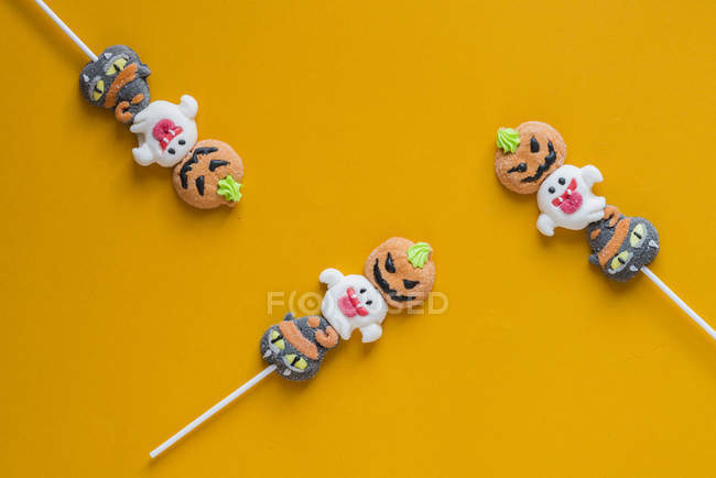 Doces de Halloween em paus no fundo laranja — Fotografia de Stock