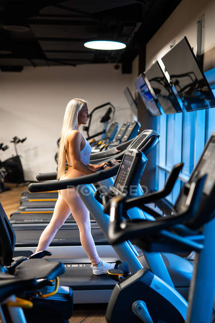 Atlético loira mulher jogging no esteira no ginásio — Fotografia de Stock