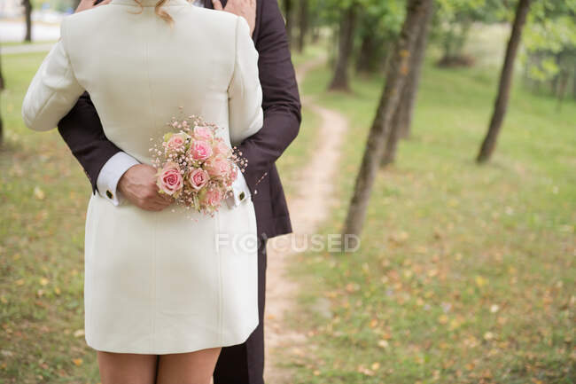 Gesichtslose Aufnahme von elegantem Brautpaar, das sich im grünen Park sinnlich umarmt — Stockfoto