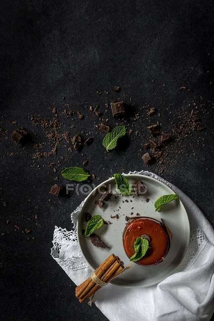 Chocolate cake with mint and cinnamon on plate on black background — Stock Photo
