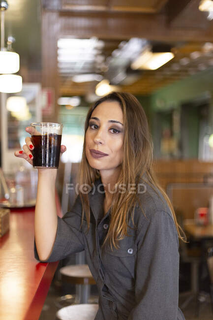 Mujer alegre sentada en la cafetería - foto de stock