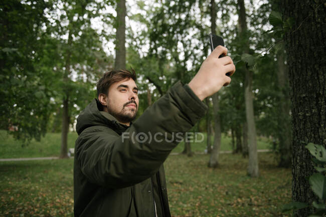Homem na floresta com telefone celular tirar foto — Fotografia de Stock