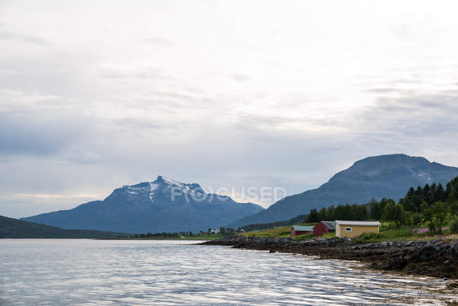 Wooden houses on river shore in mountains — Stock Photo