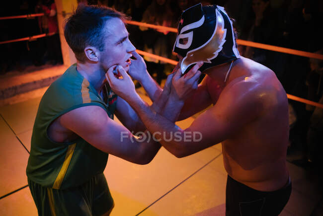 Side view of men standing in front of each other touching faces on wrestling ring — Stock Photo