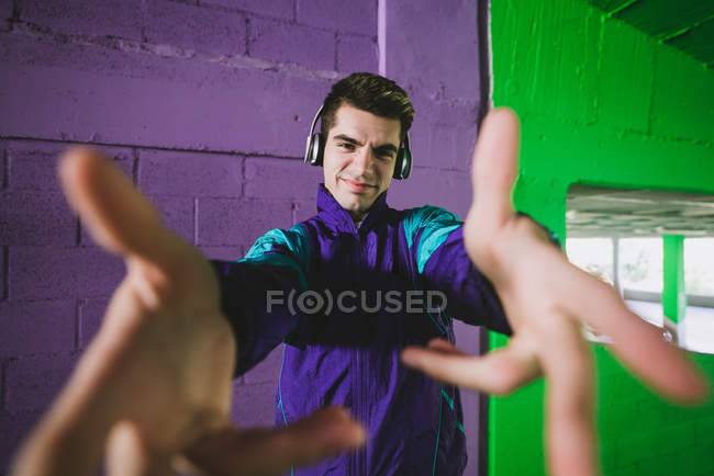 Молодой человек в спортивной одежде и наушниках, протягивающих руки к камере — стоковое фото