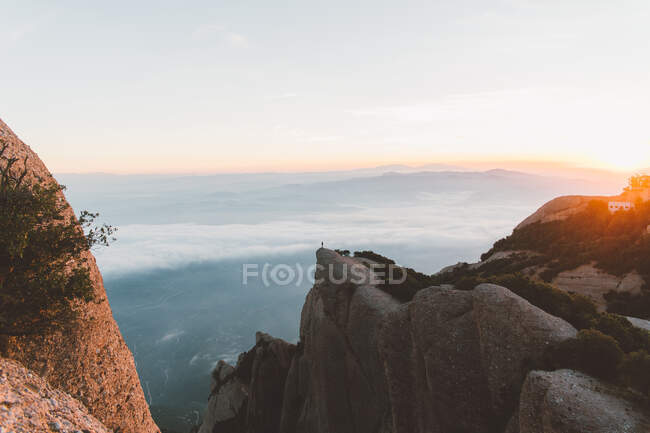 Anonymous person on cliff during sunrise — Stock Photo