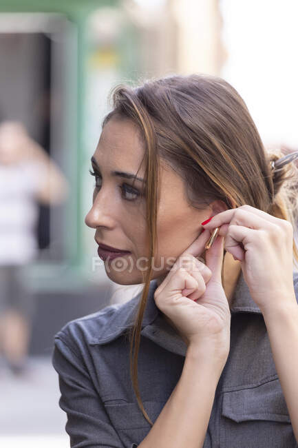 Young woman putting on earring — Stock Photo