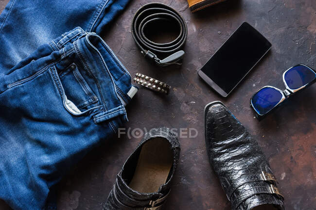 Аерофотозйомка чоловічого джинсового одягу з гаманцем, браслет для штрихів, смартфон. і чорне шкіряне взуття — стокове фото