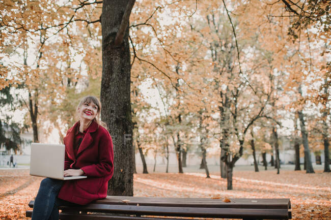 Женщина с ноутбуком сидит на скамейке — стоковое фото