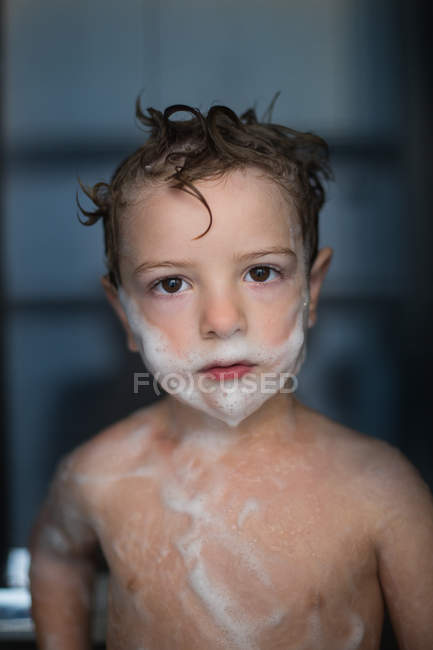 Retrato de menino com espuma no rosto e corpo no banheiro — Fotografia de Stock