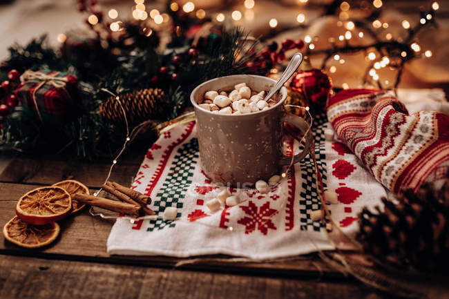 Christmas decorations and mug of hot chocolate with spices and marshmallows on wooden surface with traditional towel — Stock Photo