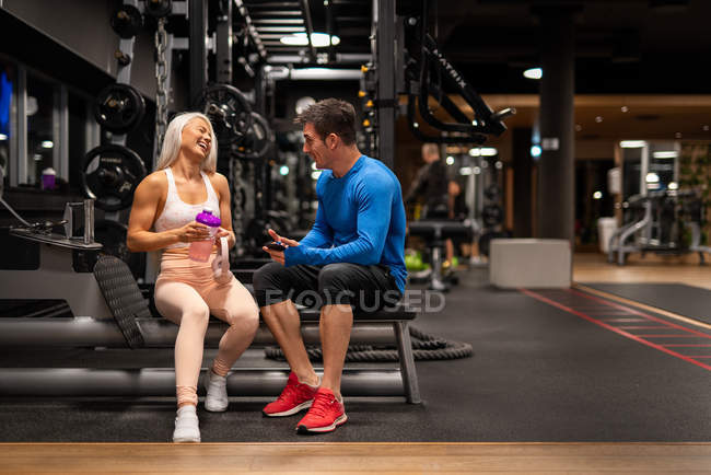 Веселий чоловік і жінка сидять у спортзалі і сміються — стокове фото