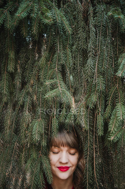 View of crop young lady's face holding coniferous branch and looking away — Stock Photo