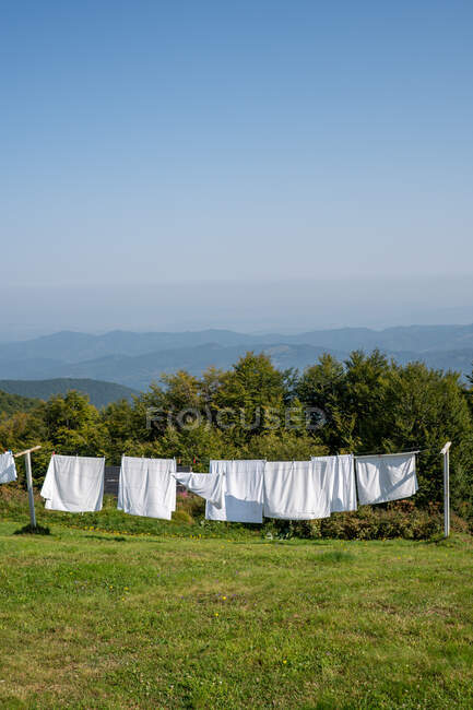 Bunch of clean white linen hanging on ropes on top of green hill on sunny day in Bulgaria, Balkans — Stock Photo