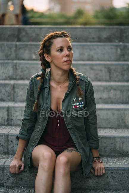 Thoughtful red-haired girl with braids sitting on stairs outdoors — Stock Photo