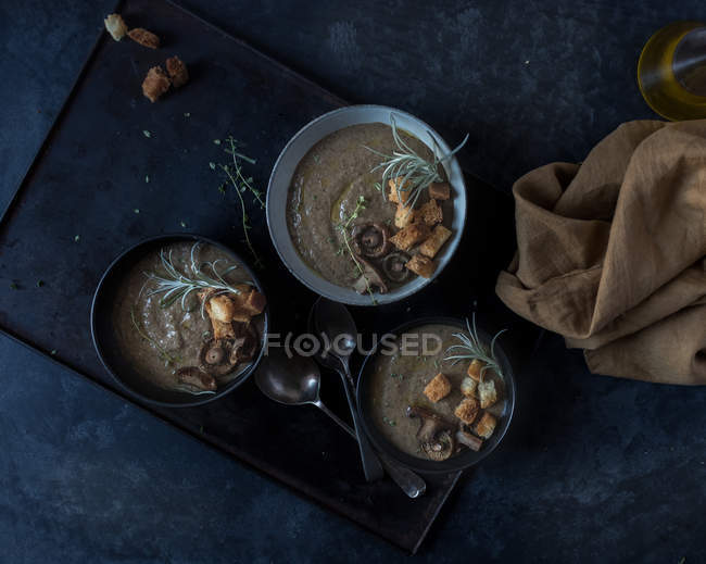Sopa de creme de cogumelos com croutons em tigelas na bandeja no fundo escuro — Fotografia de Stock