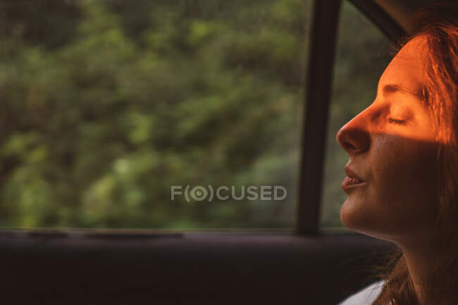 Side view of pretty young female keeping eyes closed while sitting inside modern vehicle during trip through Bulgaria, Balkans — Stock Photo