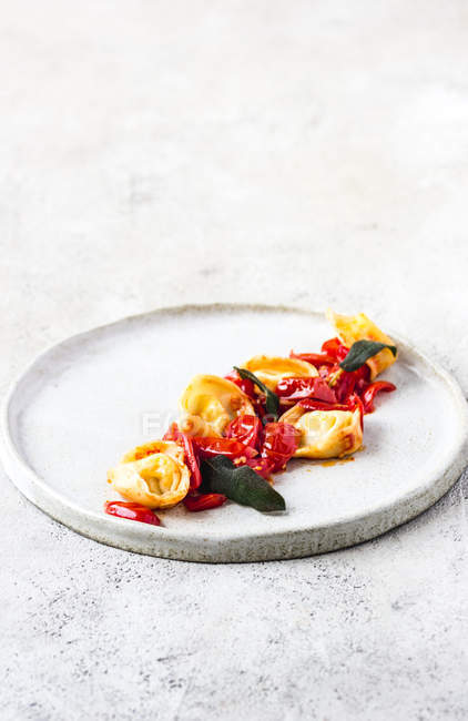 Delicious dish of tortellini with tomatoes served on plate on grey tabletop — Stock Photo