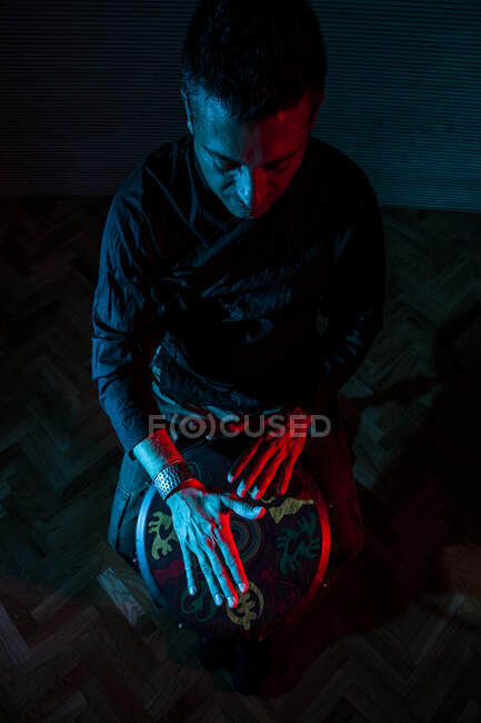 Jovem percussionista praticando técnica com o tam tam ou tambor, iluminação colorida em vermelho e azul. — Fotografia de Stock
