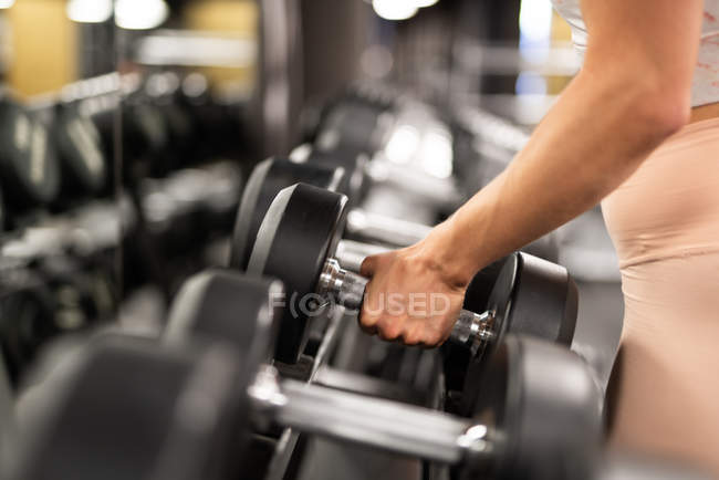 Close-up da mão feminina tomando haltere de ferro para treino no ginásio — Fotografia de Stock