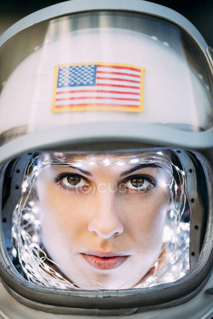 Confident girl wearing old space helmet with american flag sign on foil background — Stock Photo