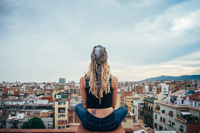 Young woman sitting on rooftop — Stock Photo