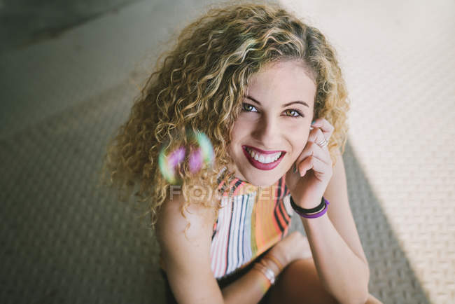 Porträt einer jungen lockigen Frau mit leuchtenden Lippen, die im Freien lächelt — Stockfoto