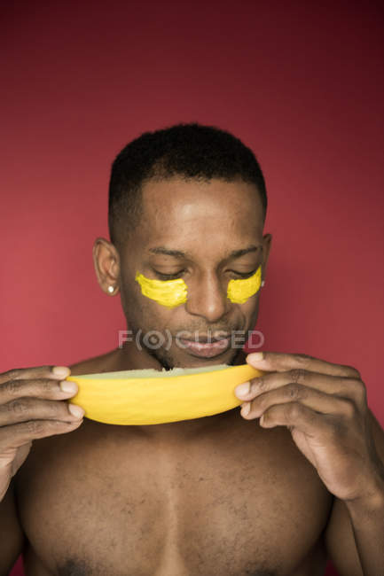 Retrato de homem sem camisa preto comendo melão com manchas amarelas no rosto — Fotografia de Stock