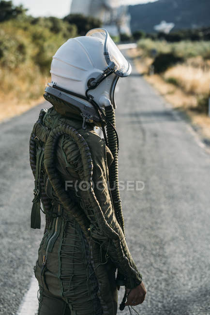 Astronautin mit Helm und Raumanzug steht auf Landstraße — Stockfoto