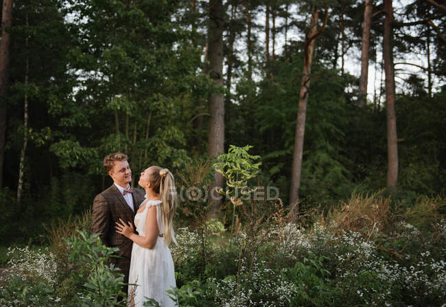 Свадебная пара смотрит друг на друга в лесу — стоковое фото
