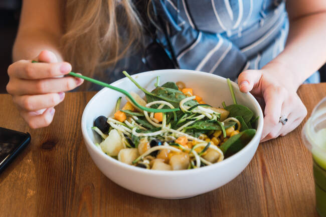 Gesichtslose Aufnahme einer Frau, die am Tisch sitzt und Salat mit Nudeln und Früchten isst — Stockfoto