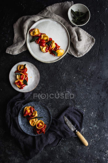 Teller mit servierten Tortellini mit Tomaten auf dunkelgrauer Tischplatte — Stockfoto