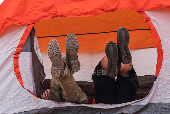 Ноги двох друзів чоловічої статі лежать в сучасному наметі під час кемпінгу разом — стокове фото