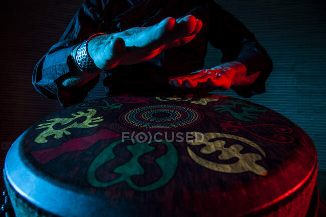 Young percussionist practicing technique with the tam tam or drum, colored lighting in red and blue.hands view — Stock Photo