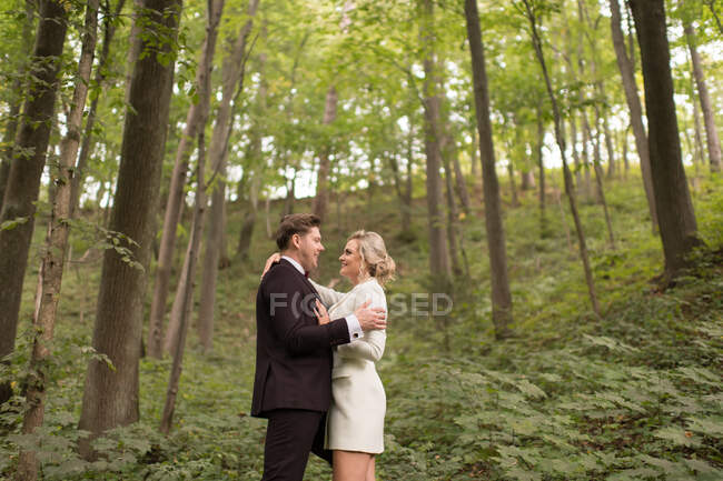 De cima tiro de abraçar noiva adulta e noivo de pé em bosques verdes — Fotografia de Stock