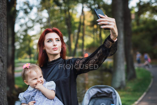Mãe tomando selfie com bebê alegre menina no parque — Fotografia de Stock