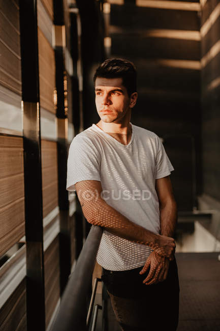 Молодий вдумливий чоловік стоїть всередині будівлі на сонячному світлі — стокове фото
