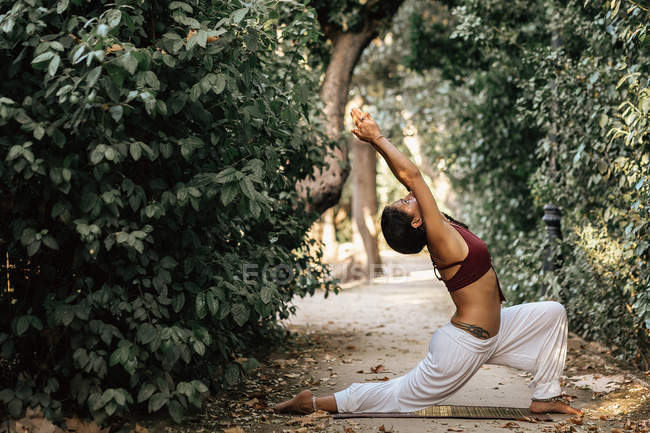 Slim woman bending back while doing yoga on alley in autumn park — Stock Photo