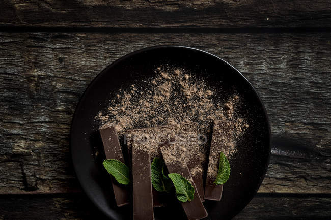Шоколадные кусочки и кусочки мяты на темном деревянном фоне — стоковое фото