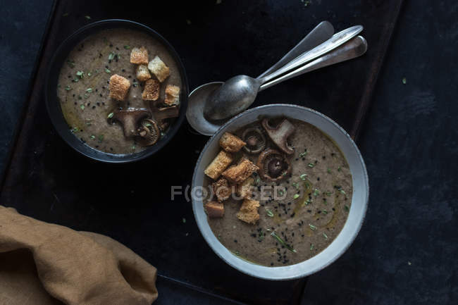 Mushroom cream soup with croutons in bowl on black tray — Stock Photo