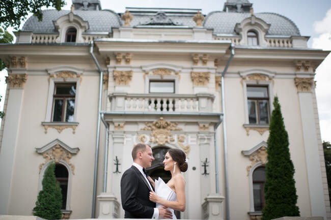 Casal casal abraçando perto de edifício de luxo — Fotografia de Stock